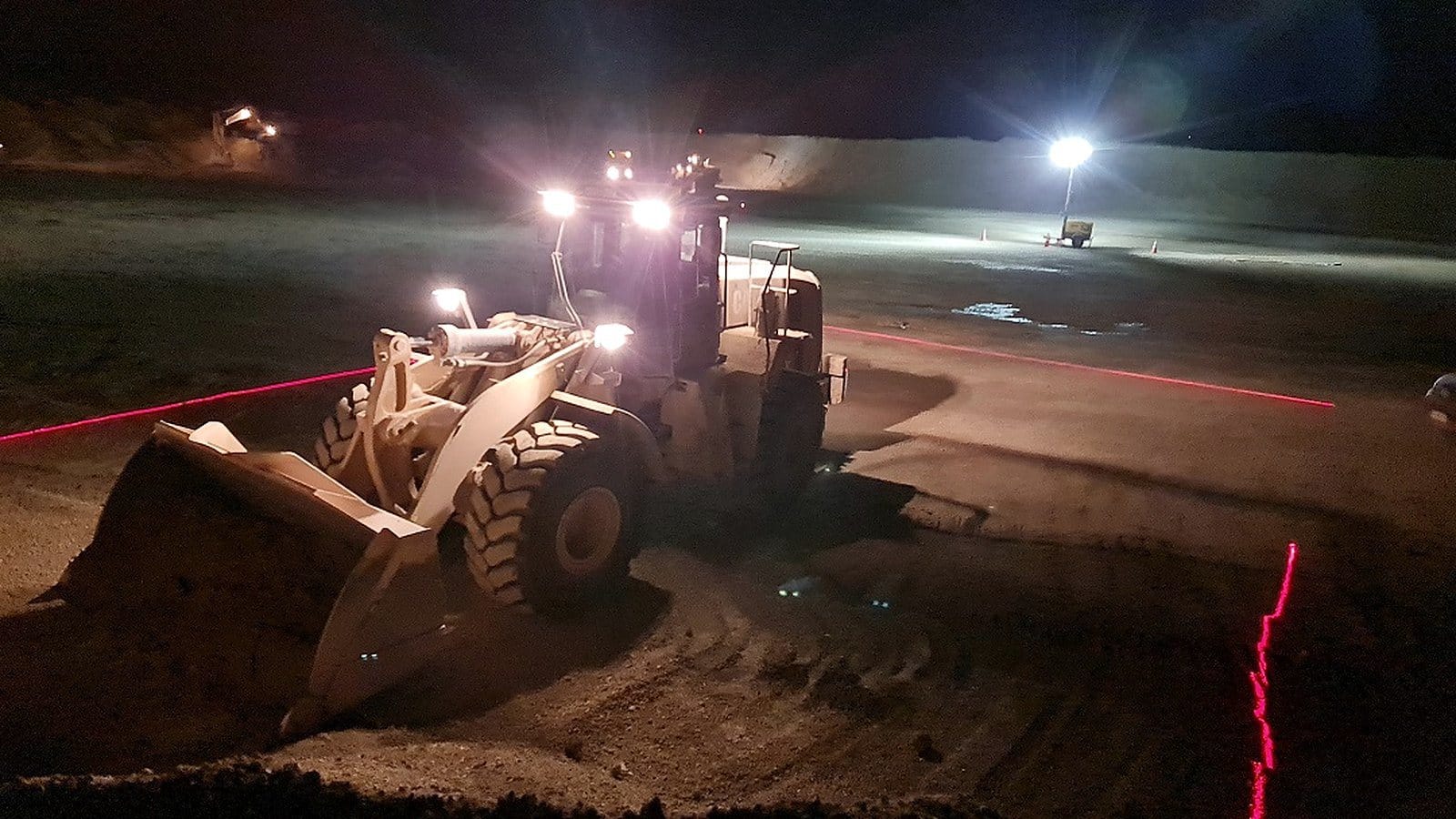 Cargador con línea láser roja en operación nocturna